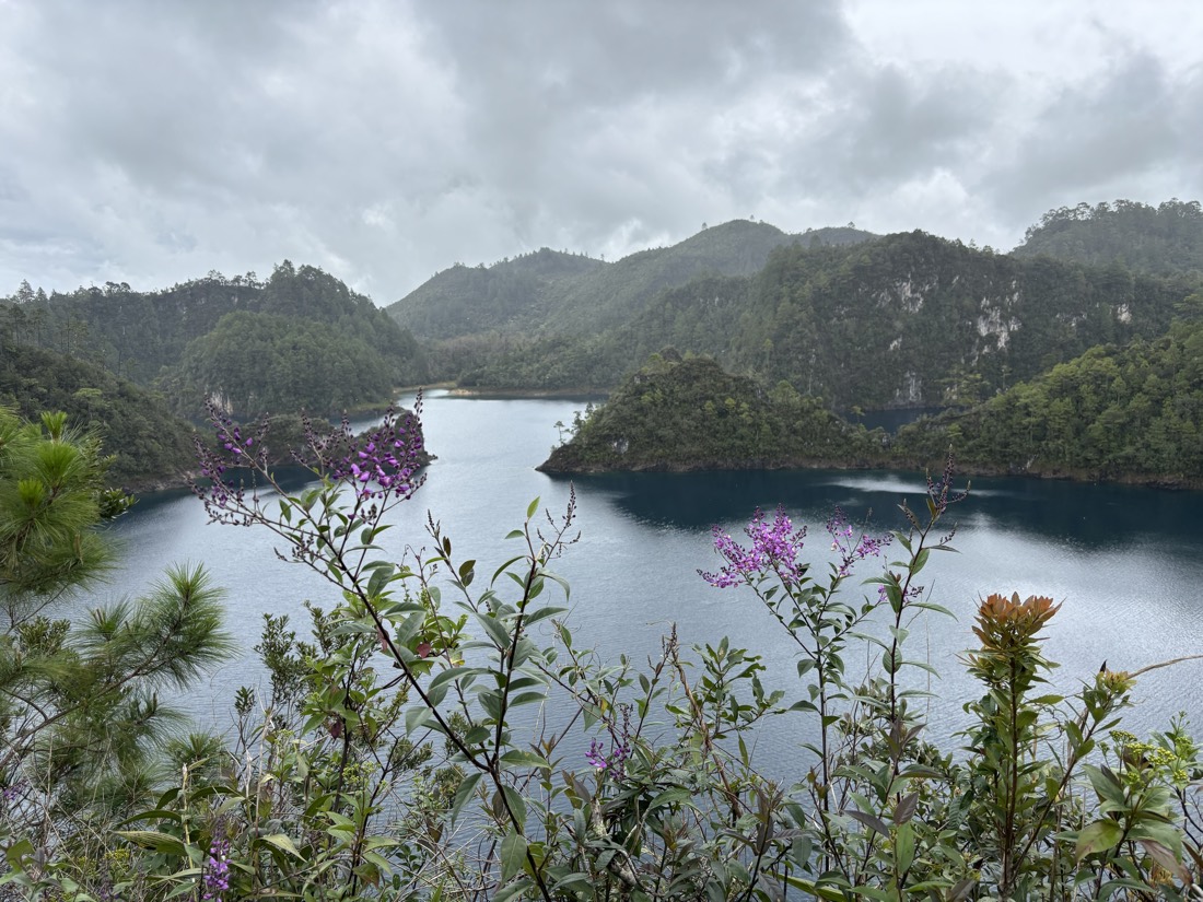 Laguna con una pequeña isla rodeada de montañas verdes
