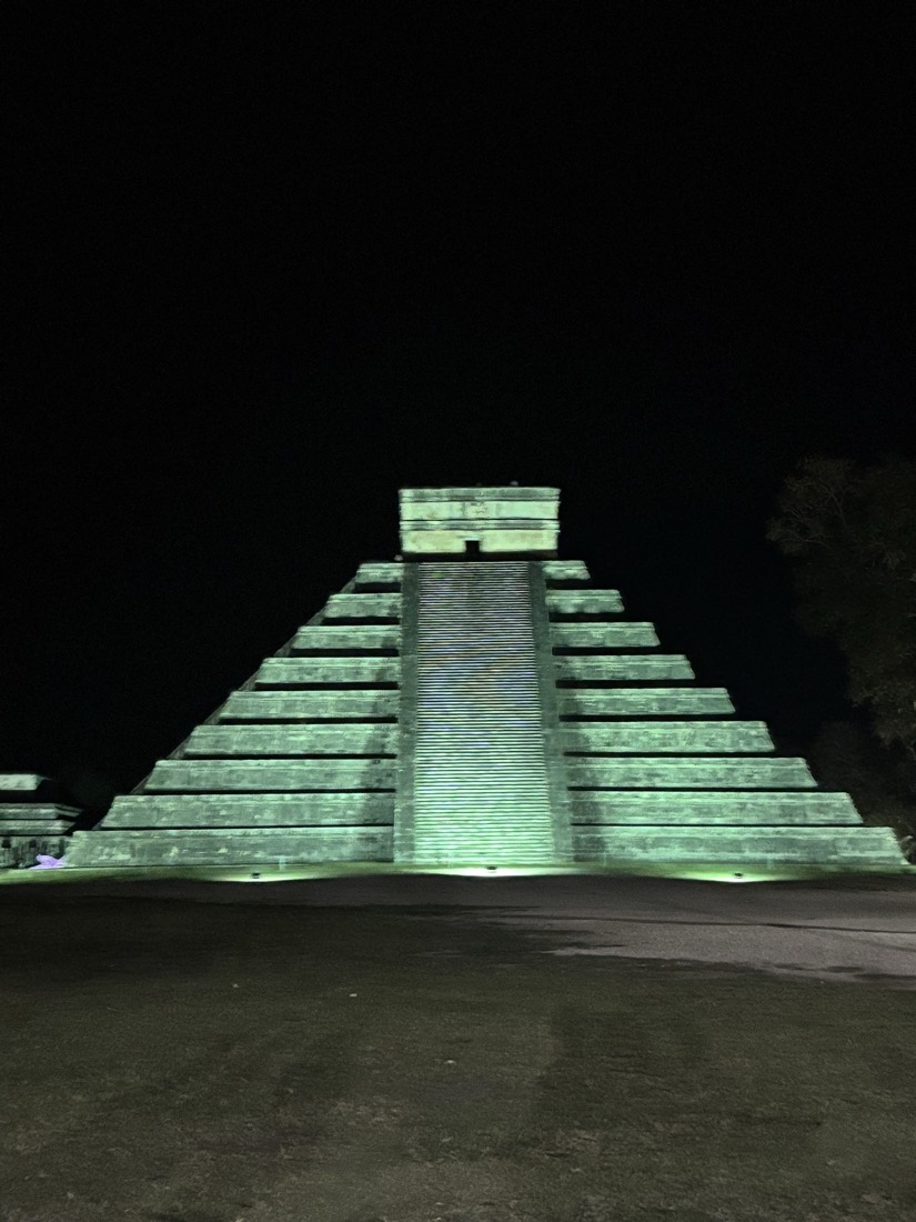 Pirámide arqueológica iluminada de verde por la noche